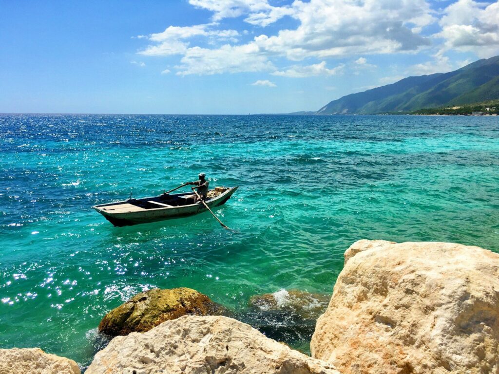 man in red shirt riding on boat on sea during daytime